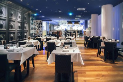 A restaurant with tables and chairs covered in white cloth.